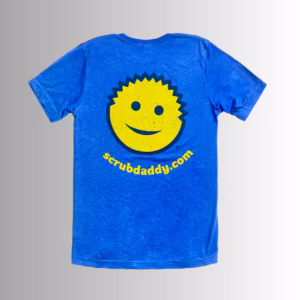 Image Description: A promotional product image showing the back of the royal blue short-sleeve t-shirt set against a neutral gradient background, featuring a large yellow smiley-face graphic with dark blue outlines and facial features above the yellow URL text "scrubdaddy.com"