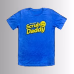Image Description: A promotional product hero image of the front of a royal blue short-sleeve t-shirt set against a neutral gradient background, featuring the yellow "The Original Scrub Daddy" logo printed across the chest.
