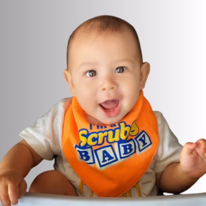 Image Description: A lifestyle hero photo of a baby smiling in a high chair against a neutral gradient background, wearing an orange bandana-style baby bib featuring the text "I'm a Scrub Baby" with a smiley face icon.