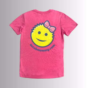 Image Description: A promotional product image showing the back of the vibrant pink short-sleeve t-shirt set against a neutral gradient background, featuring a large yellow smiley-face graphic wearing a pink bow, outlined in dark blue, above the purple URL text "scrubmommy.com".