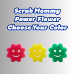 Image Description: Promotional image for Scrub Mommy Power Flower Choose Your Color, featuring large blue text at the top that reads "Scrub Mommy Power Flower Choose Your Color." Below the text, three flower-shaped Scrub Mommy sponges are lined up horizontally: a pink one on the left, a yellow one in the middle, and a green one on the right, each featuring a smiling face cutout.