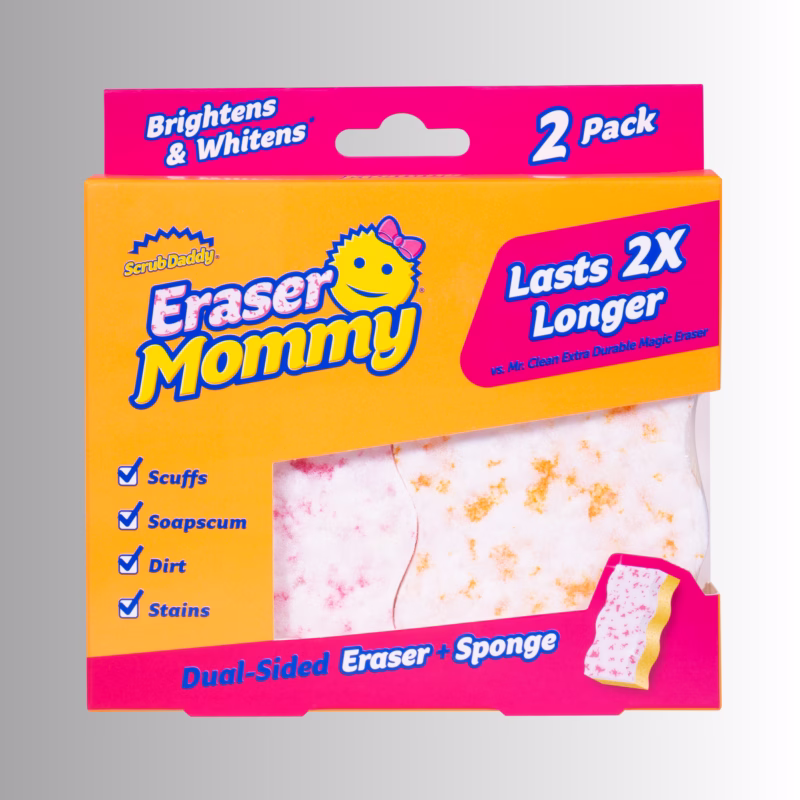 Eraser Mommy 2 Pack Image Description: Packaging for a Scrub Daddy Eraser Mommy 2-pack, featuring an orange and bright pink cardboard box with blue text that reads "Brightens & Whitens," "2 Pack," "Lasts 2X Longer," and "Dual-Sided Eraser + Sponge." The front of the box also lists cleaning features with checkmarks for "Scuffs," "Soapscum," "Dirt," and "Stains," and shows a cutout window displaying the textured dual-sided eraser pads inside.