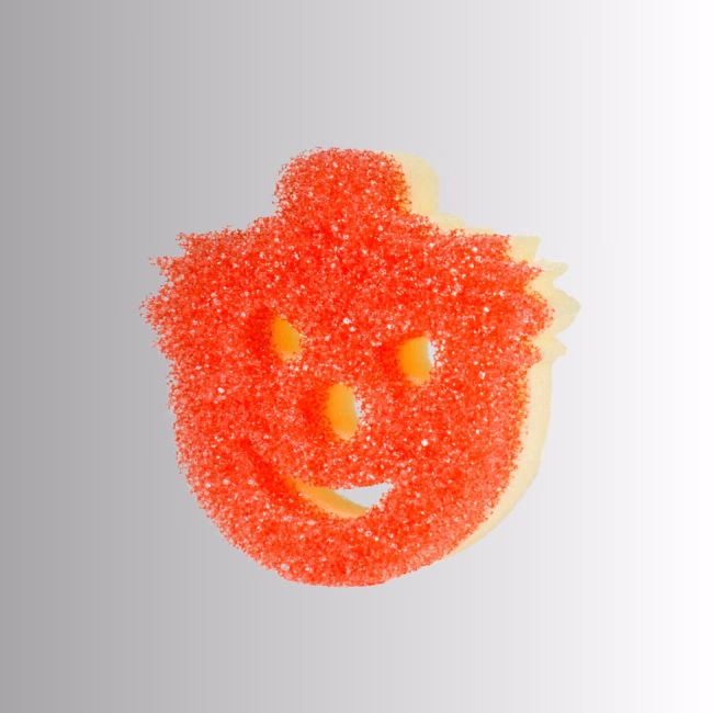 Image Description: A red-textured clown or circus-themed character Scrub Mommy sponge displayed against a neutral gray and white gradient background, featuring a bright red scrubbing side with a carved smiley face and a visible light yellow foam backing.