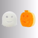 Image Description: A white ghost-shaped Scrub Daddy or Scrub Mommy sponge on the left and an orange pumpkin-shaped sponge on the right, displayed side-by-side against a neutral gray and white gradient background.