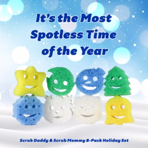 A holiday-themed promotional graphic against a snowy blue background with bokeh light effects. Large blue text at the top reads "It’s the Most Spotless Time of the Year." In the center, eight holiday-shaped Scrub Daddy and Scrub Mommy sponges are arranged in two rows: the top row features a yellow star, a green round ornament, a blue round ornament, and a green Christmas tree; the bottom row features a blue snowflake, a white bear, a white snowman, and a yellow bell. Blue text at the bottom reads "Scrub Daddy & Scrub Mommy 8-Pack Holiday Set."
