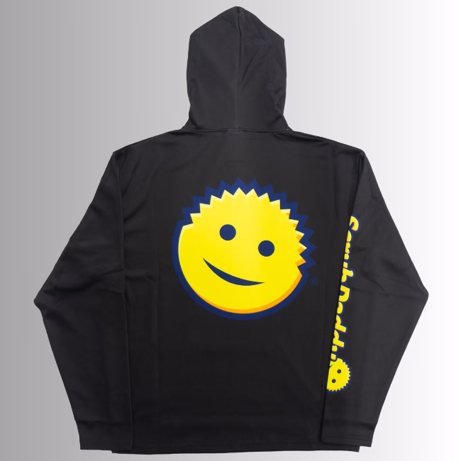 Image Description: A promotional product hero image showing the back of the black Scrub Daddy hoodie set against a neutral gradient background, featuring a large yellow smiley face graphic centered on the back and yellow branding text running down the right sleeve.
