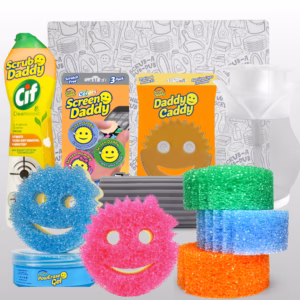 A collection of Scrub Daddy cleaning products arranged on a light grey background, showcasing a large cleaning bundle. In the background stands a white dish drying mat patterned with grey line-art illustrations of cleaning supplies. Arranged from left to right in the middle row are a yellow bottle of Scrub Daddy Cif All Purpose Cleaning Cream, a 3-pack of Screen Daddy microfiber pads in orange packaging, a clear Daddy Caddy sponge holder in orange packaging, a grey ridged Damp Duster, and a white and clear Soap Daddy dispenser. In the foreground on the left is a blue tub of PowErase Gel with a blue Scrub Mommy sponge resting on top, a pink Scrub Mommy sponge in the center, and a stack of three Scrub Daddy Colors sponges (green, blue, and orange) on the right.