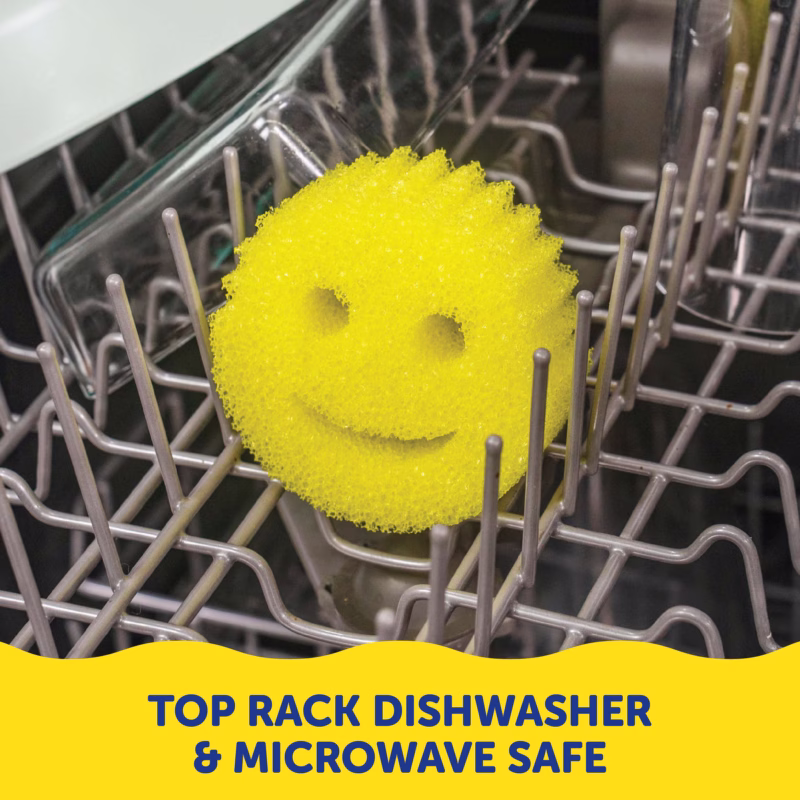 A yellow Original Scrub Daddy sponge resting on the grey tines of a dishwasher rack. A yellow banner at the bottom contains dark blue text that reads, "TOP RACK DISHWASHER & MICROWAVE SAFE".