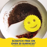 A top-down view of a dirty frying pan where half of the burnt, stuck-on grime has been wiped completely clean. A yellow Scrub Daddy sponge rests on the clean section. A yellow banner at the bottom contains dark blue text that reads, "SCRATCH-FREE ON OVER 25 SURFACES*" with smaller text below stating, "*Independent lab verified. Use as directed."