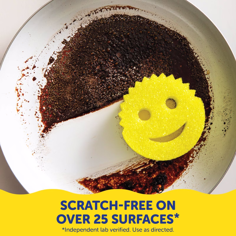 A top-down view of a dirty frying pan where half of the burnt, stuck-on grime has been wiped completely clean. A yellow Scrub Daddy sponge rests on the clean section. A yellow banner at the bottom contains dark blue text that reads, "SCRATCH-FREE ON OVER 25 SURFACES*" with smaller text below stating, "*Independent lab verified. Use as directed."