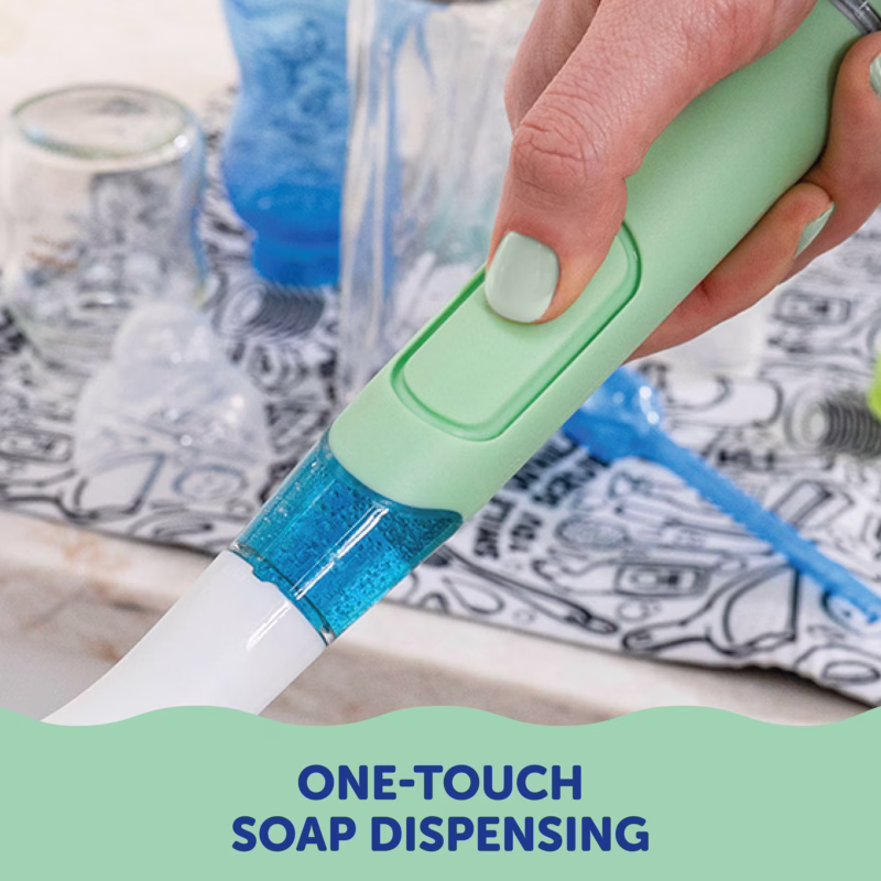 Image Description: A product feature photo showing a hand demonstrating the one-touch soap dispensing button on the light green Scrub Baby wand.