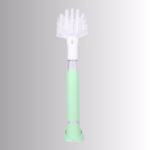 Image Description: A promotional product hero image of the Scrub Baby bristle brush set against a neutral gradient background, featuring a light green and white soap-dispensing wand with a white bristle head.