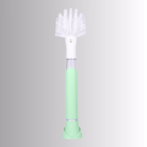 Image Description: A promotional product hero image of the Scrub Baby bristle brush set against a neutral gradient background, featuring a light green and white soap-dispensing wand with a white bristle head.